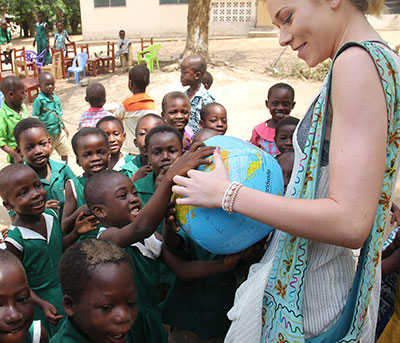 travel abroad student points to where she's from on a globe for young schoolchildren in Nicaragua