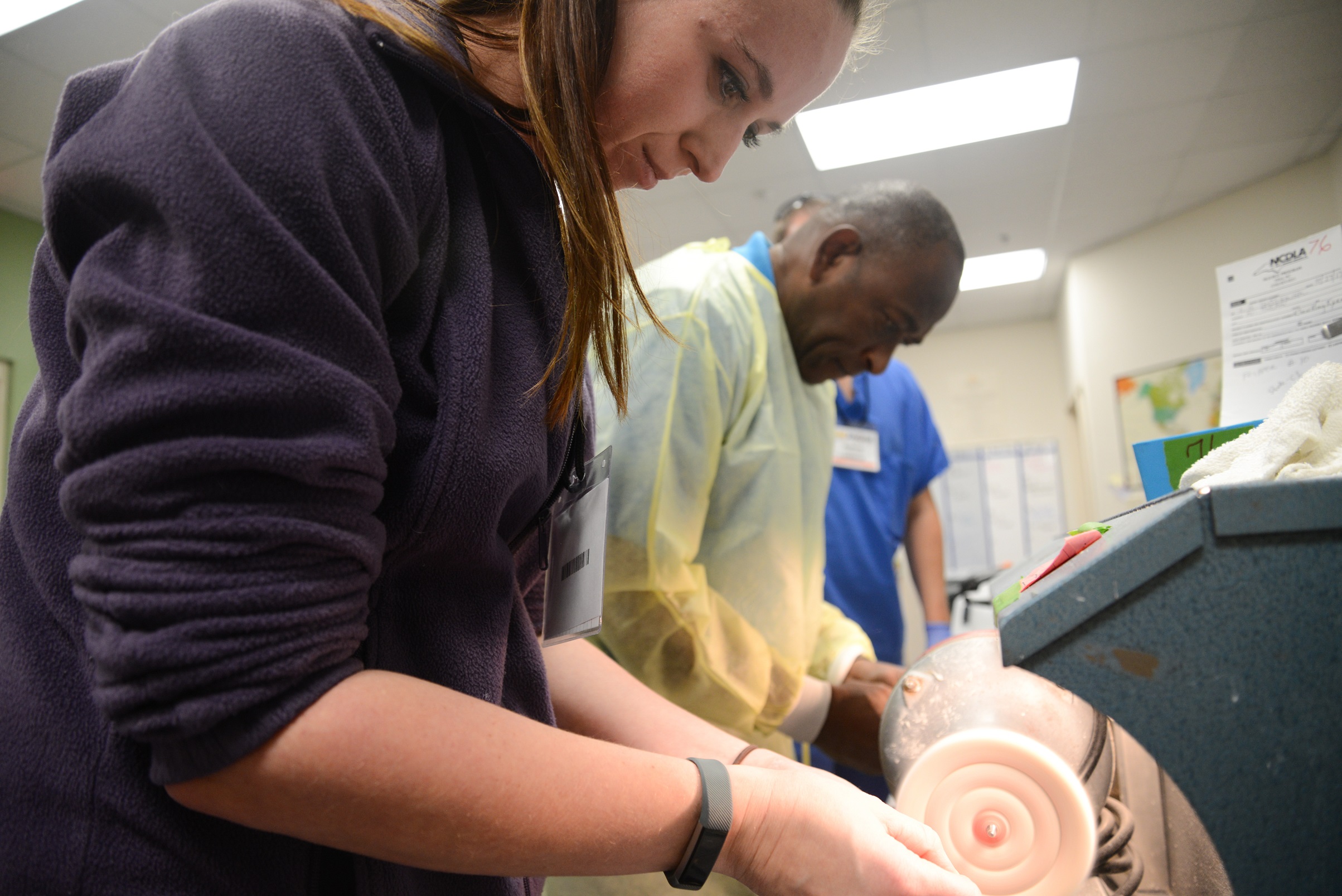 student and program director use machine to shape dentures