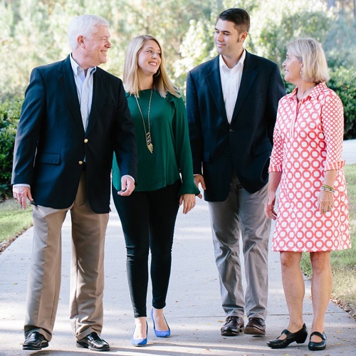 Griffin family walking down sidewalk smiling at each other on sunny day on main campus