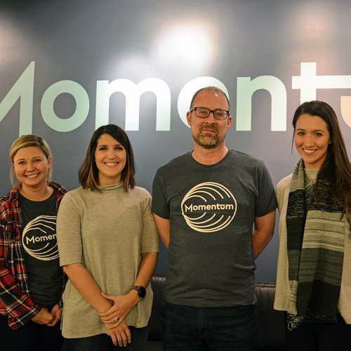 Momentum cofounders pose with students under company logo