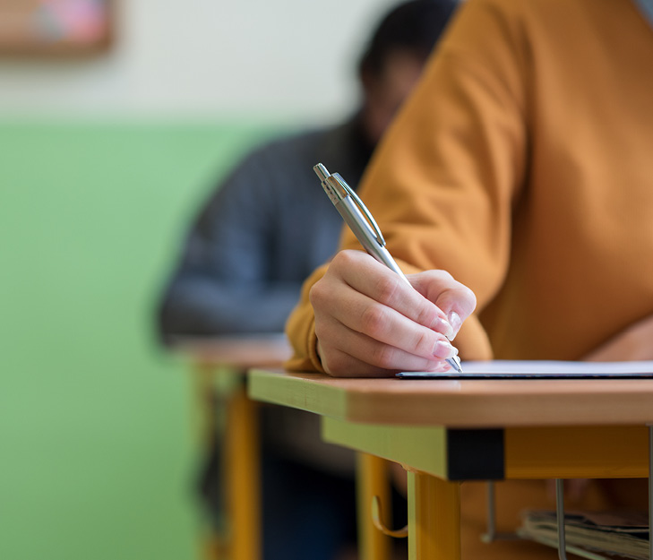 student sitting at desk in class writing on paper