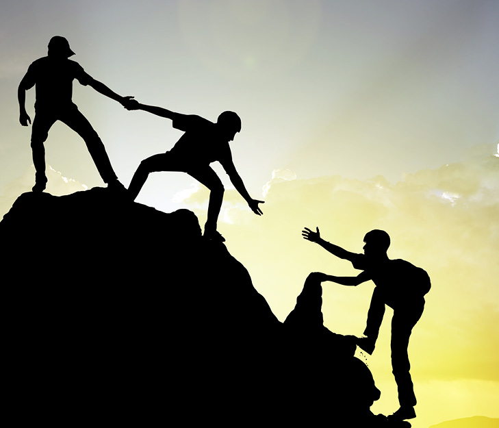 two people reaching out a hand to help another up a mountain