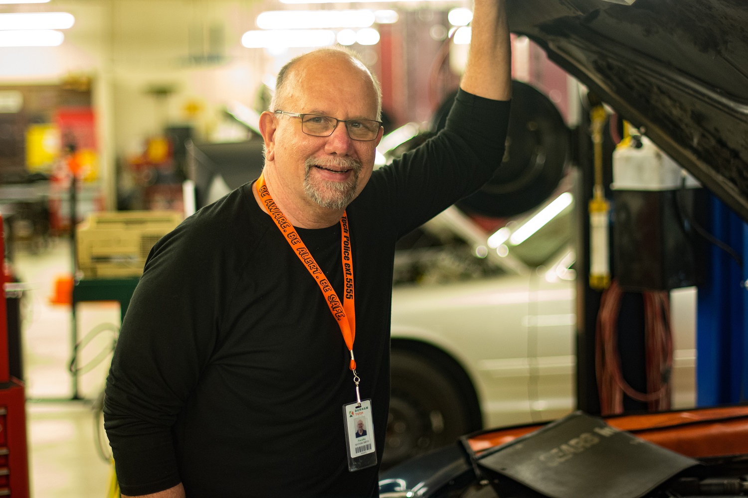 nate smith smiling while standing in front of car, hand up on hood of car