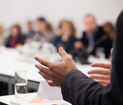 partial view of an instructor standing in front of a classroom of students