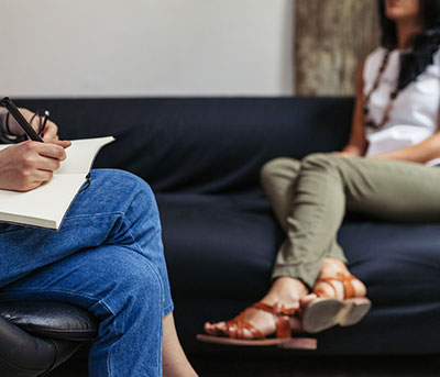 student sitting on sofa talking to a person taking notes