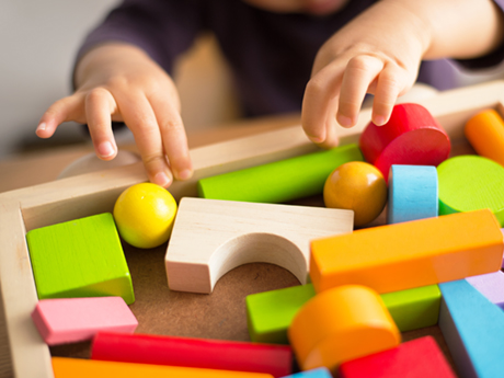child's hands playing with block toys 