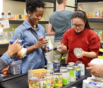 Smiling students marking donated cans and stocking shelves