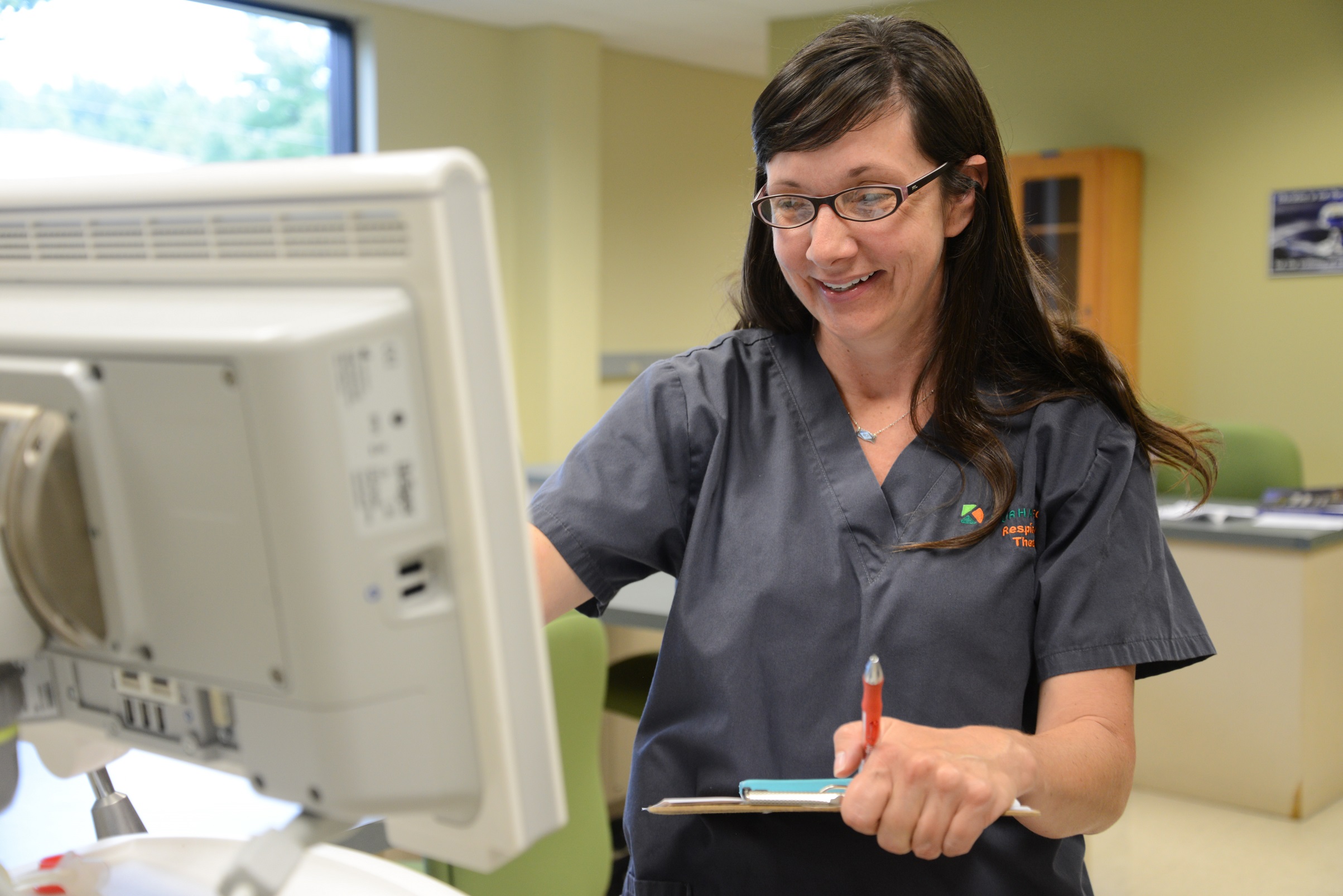 molly smiling standing in front of respiratory machine pushing button