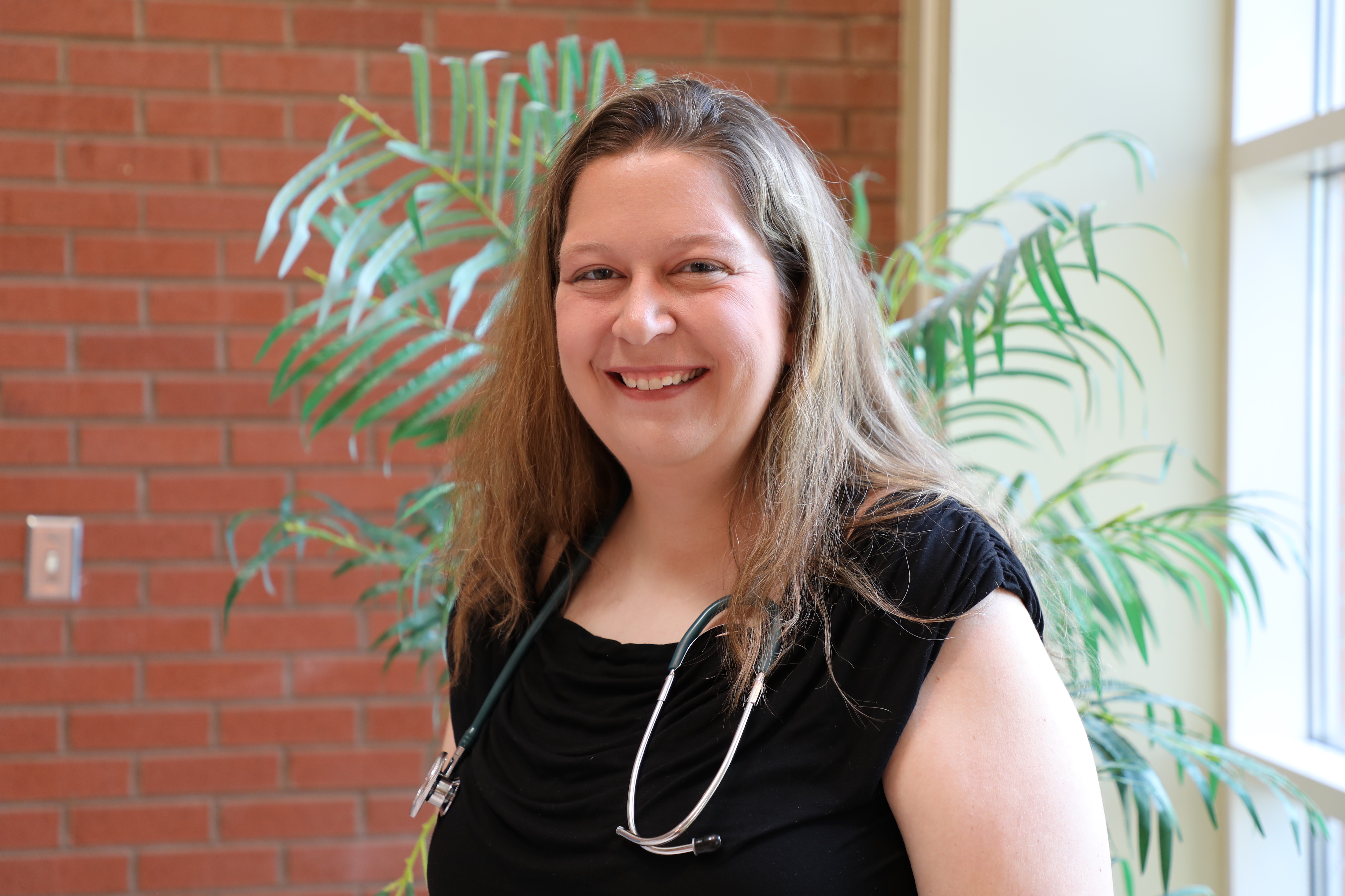 lauren smiling in front of greenery, headshot