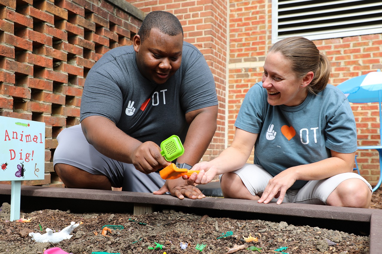 two students kneeling in front of garden bed