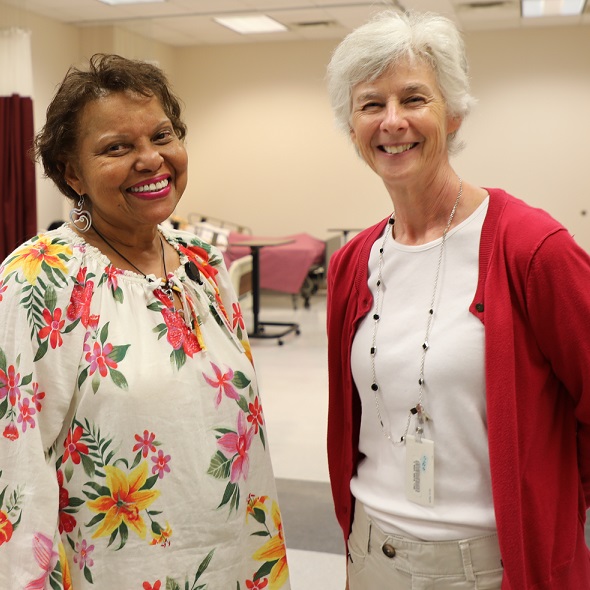 two people smiling at camera standing in nursing lab