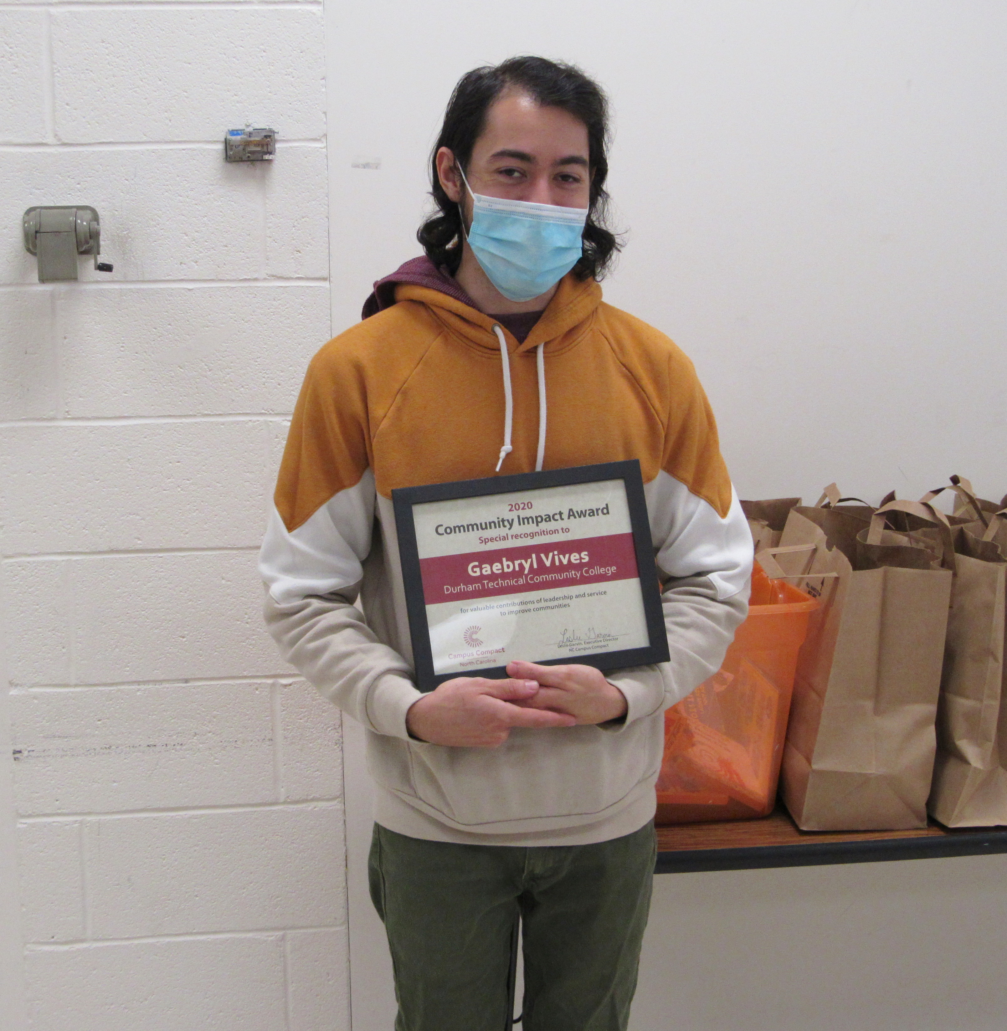student holding award, wearing mask