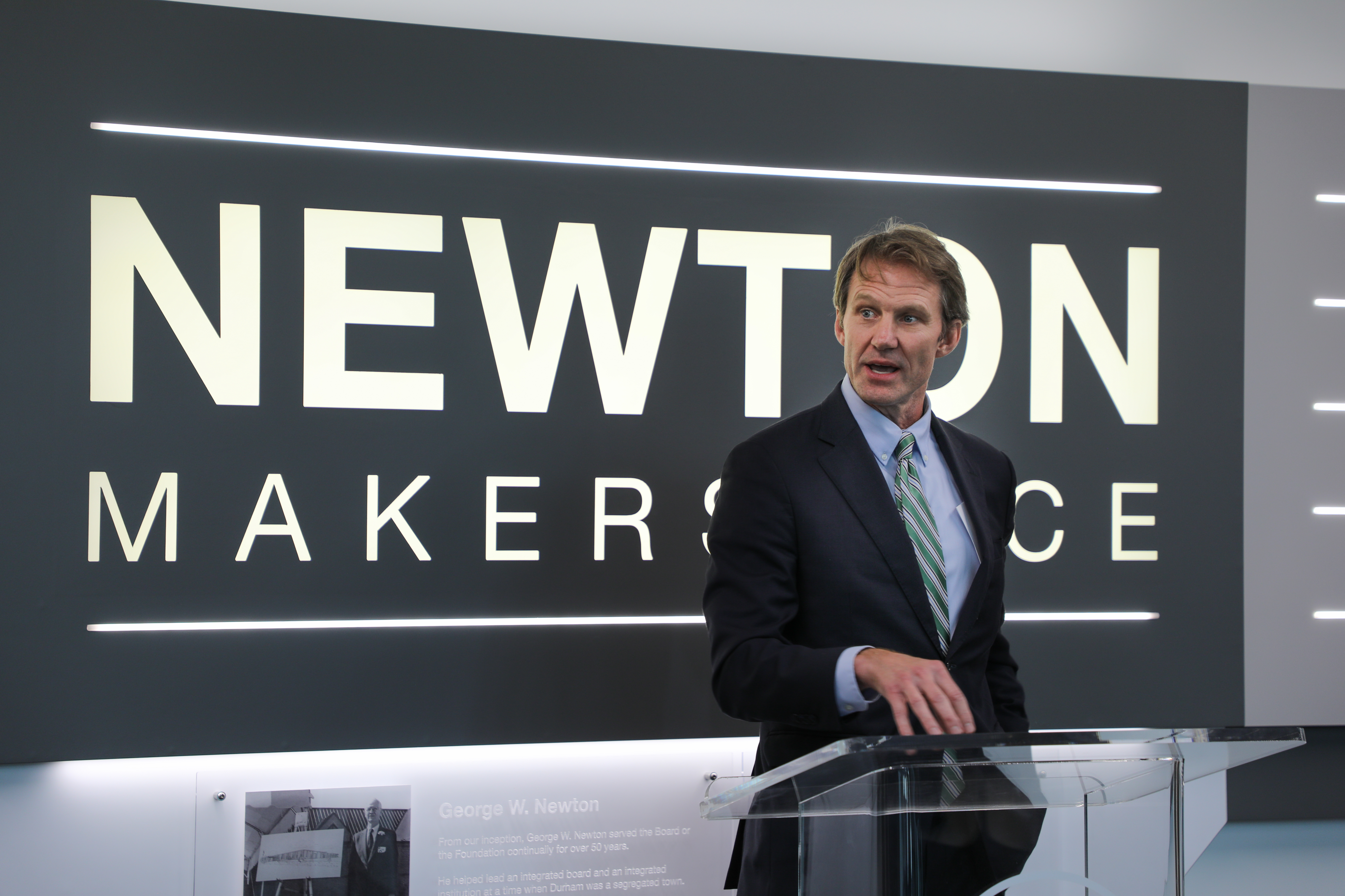 person speaking in front of sign 