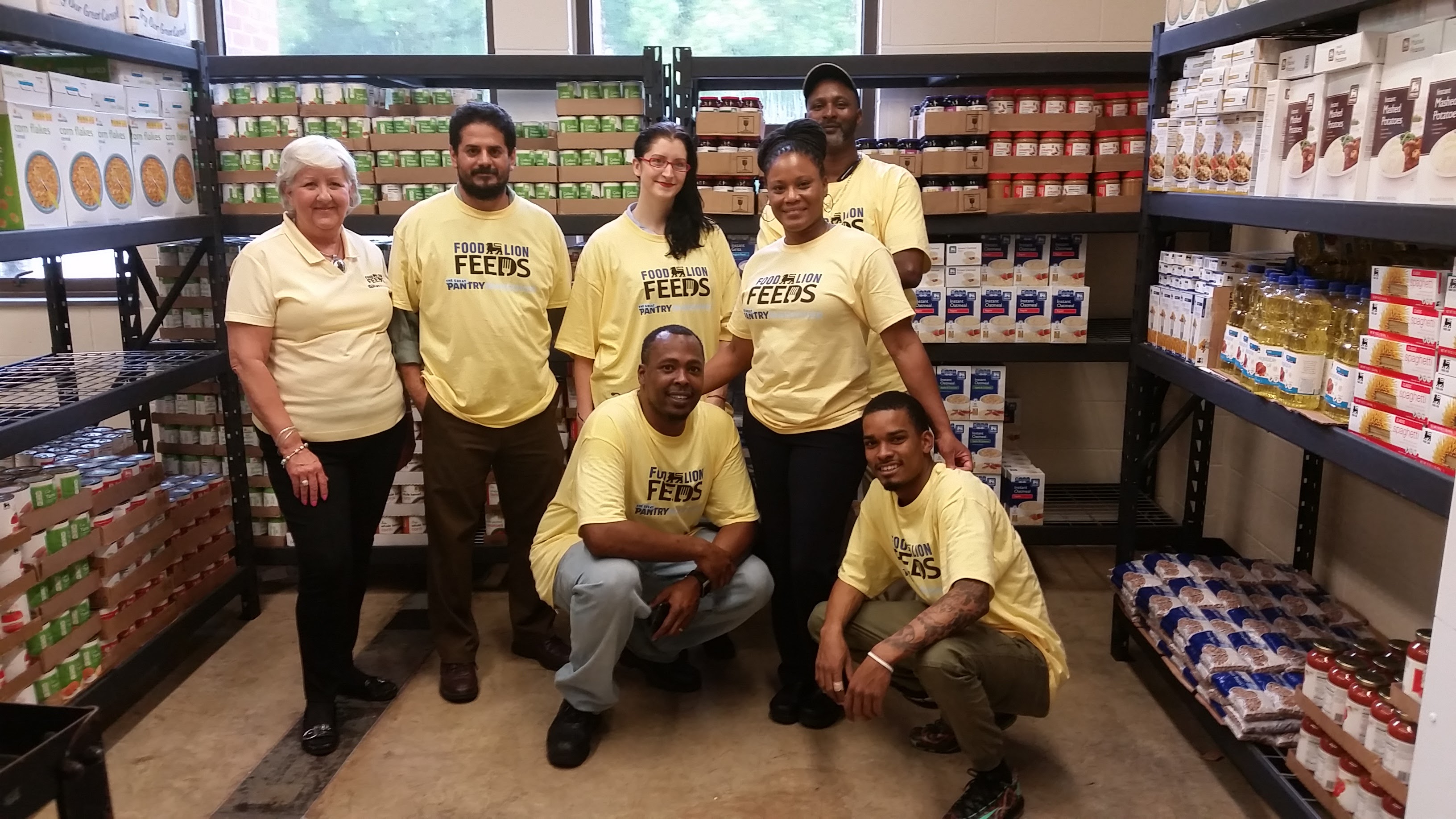 people smiling in front of shelves of food