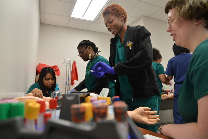 phlebotomy students practicing taking blood on mannequin arms