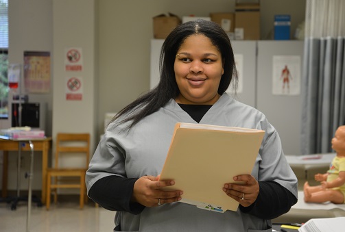 student standing and smiling holding a folder