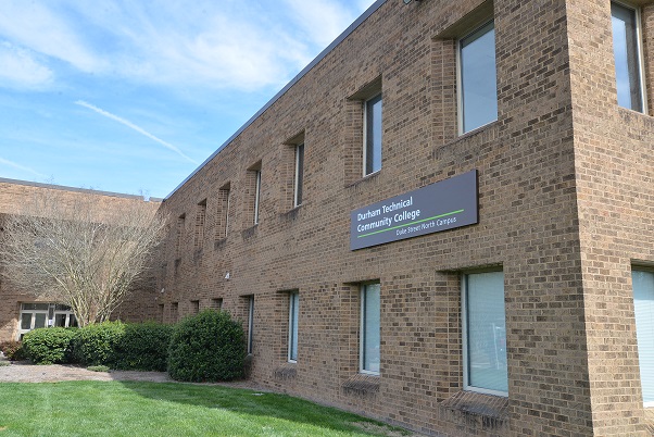 photo of brick building with college name on it, grass in front