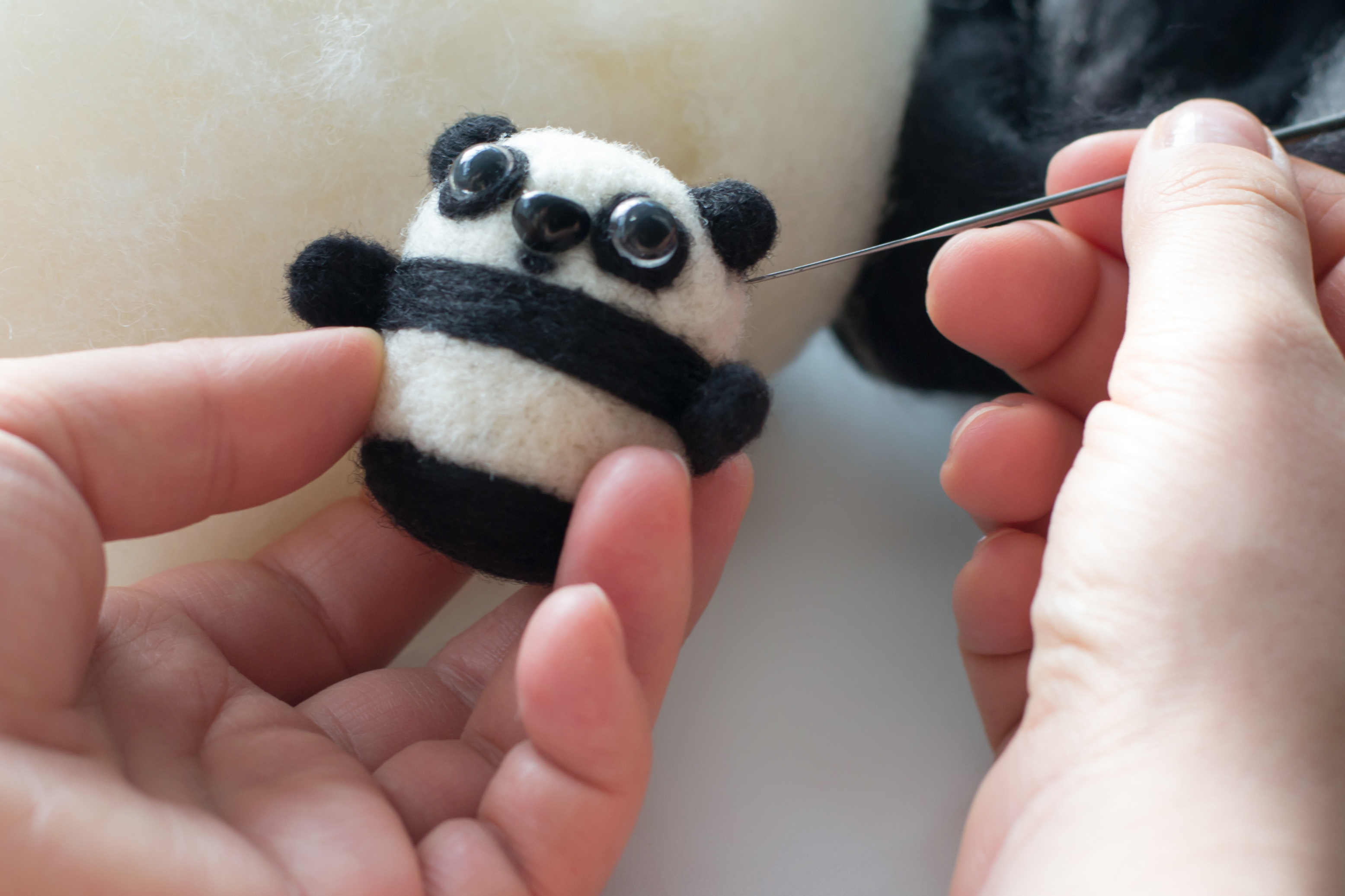 two hands holding wool felted panda