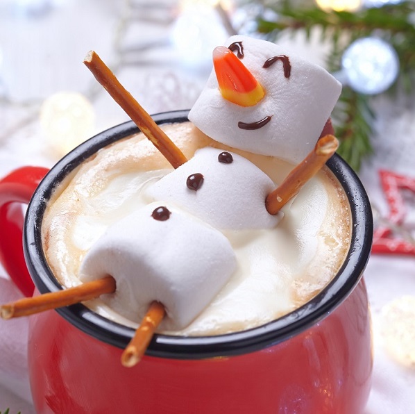 Marshmallow snowman laying in cup of hot chocolate