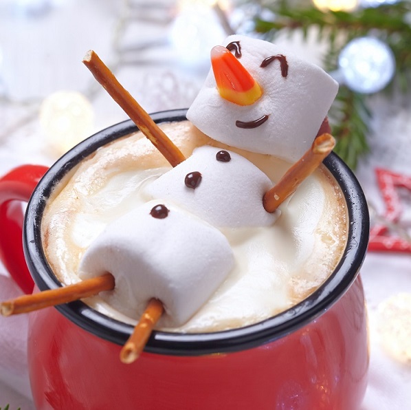 marshmallow snowman relaxing on it's back in a mug of hot chocolate