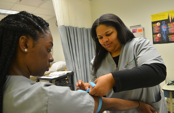 student pretending to draw blood from another student, mock appointment