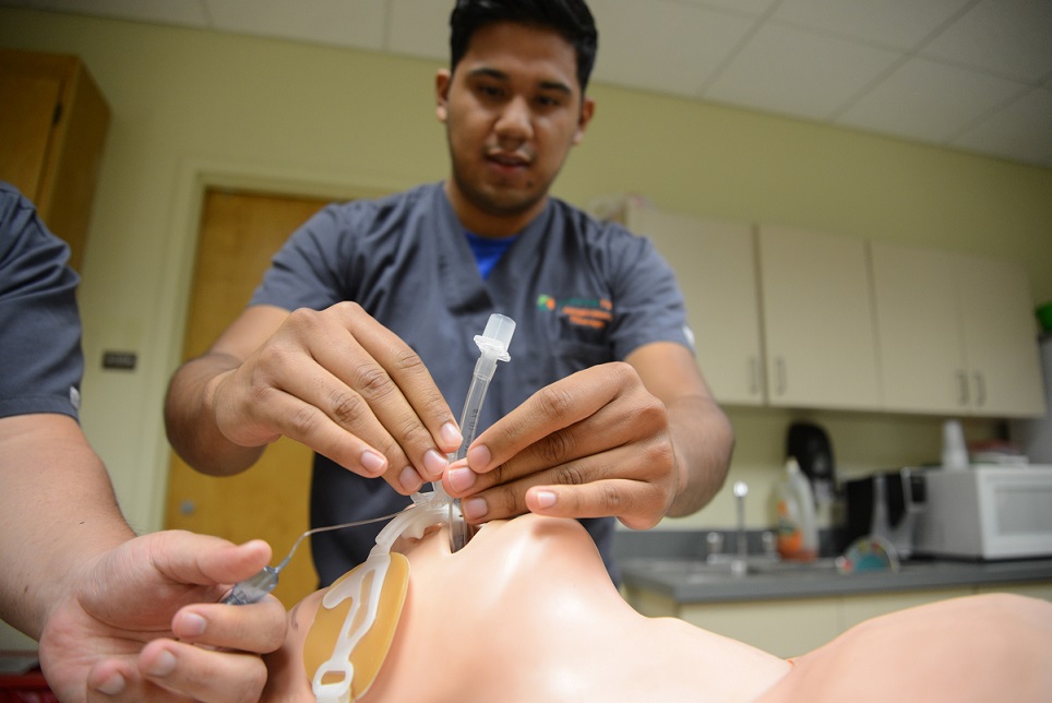 student holding intubation tube over mannequin's mouth