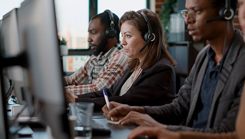 woman and men on headsets looking at computer monitors