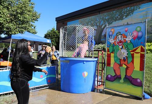 student throws a ball at a target to dunk a clown