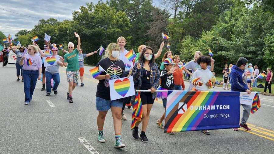 2022 student pride march with Durham Tech rainbow banner and President Buxton in the middle of the marchers