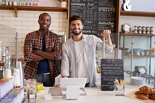 business owners of a coffee shop pose behind the counter