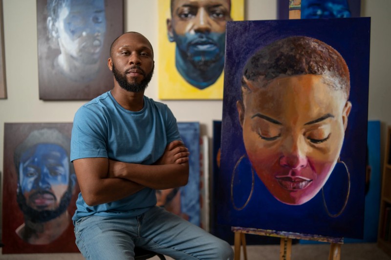 Visual artist William Paul Thomas poses next to one of his paintings.