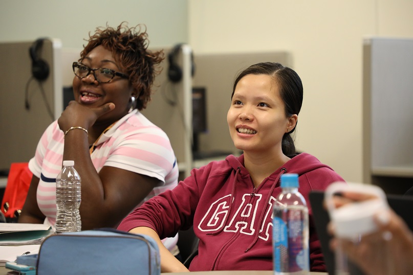 two students sitting at desk and looking ahead smiling