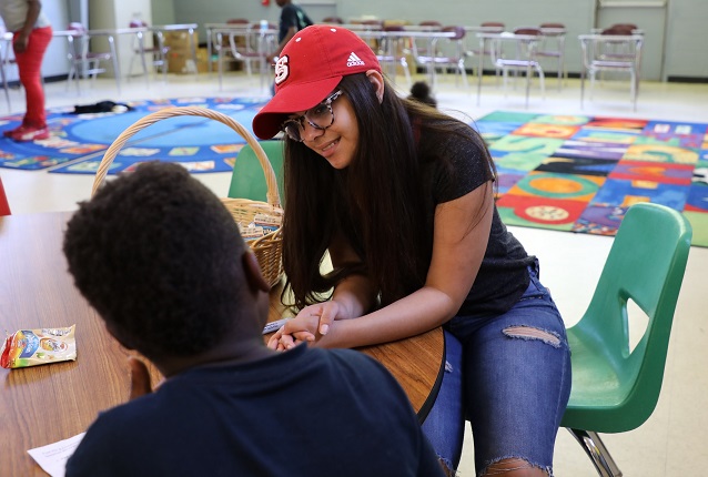 student sitting at table with young student