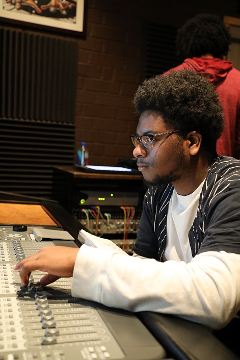 student in front of recording equipment, moving buttons