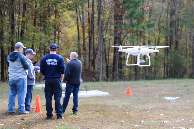 close up of drone flying and four people standing in background