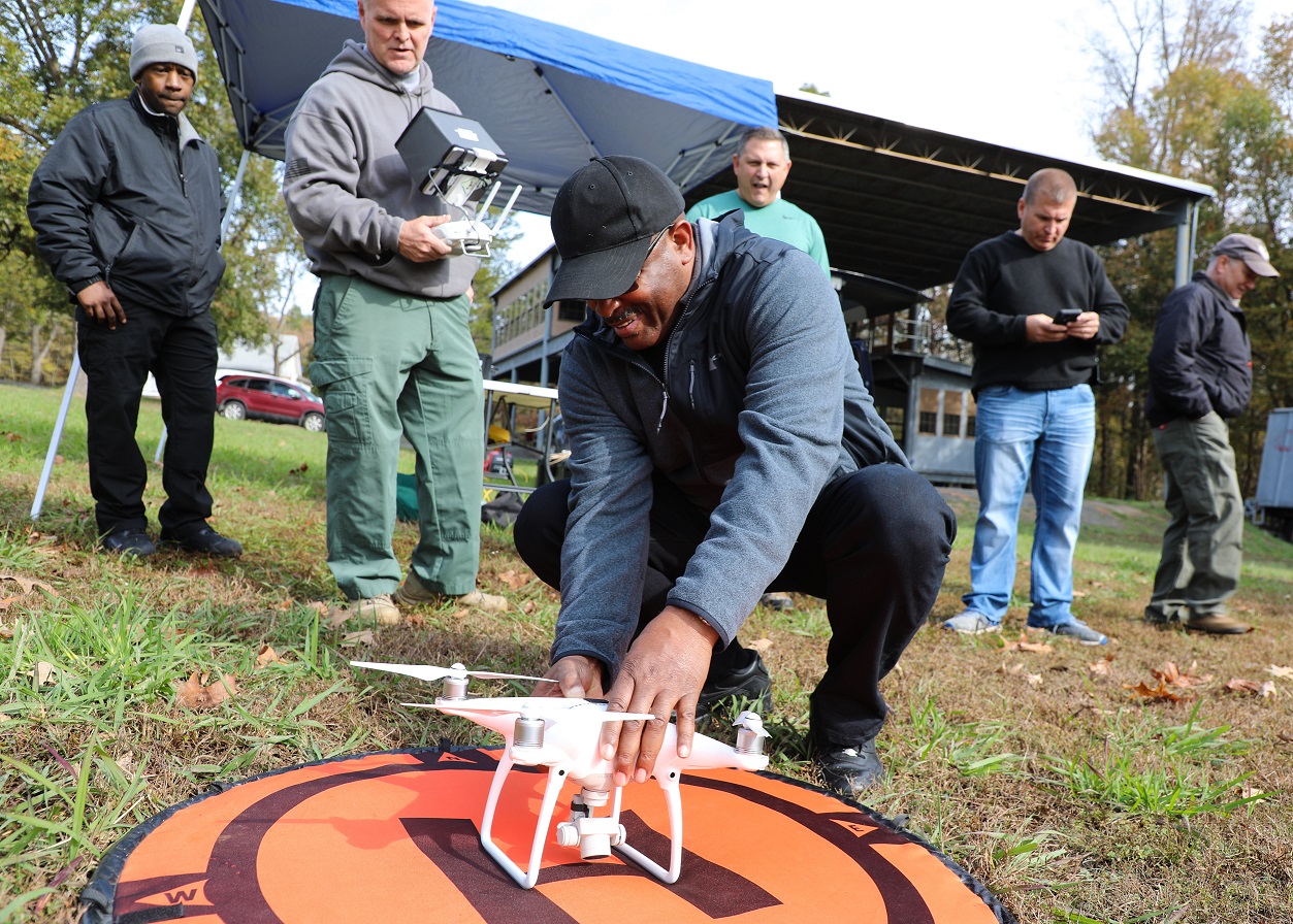 first responder squats on ground and leans over drone