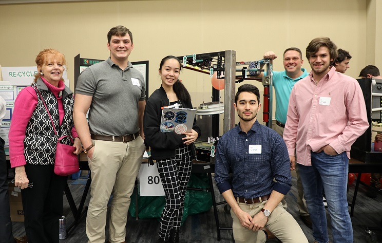 group of five students and faculty sponsor standing in front of project smiling