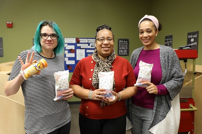three people smiling at camera holding popcorn
