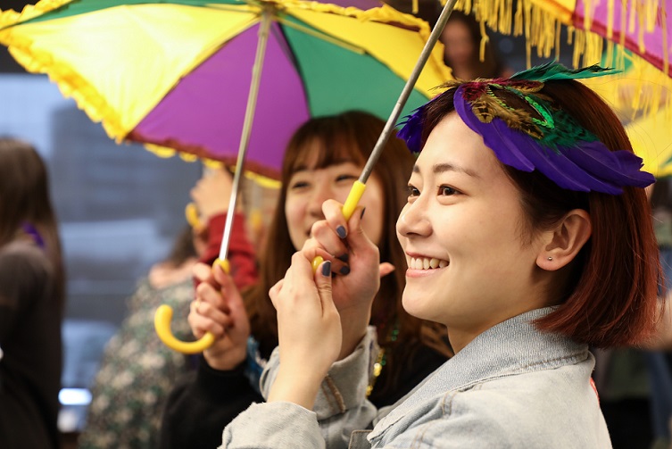 students holding mardi gras umbrella and singing