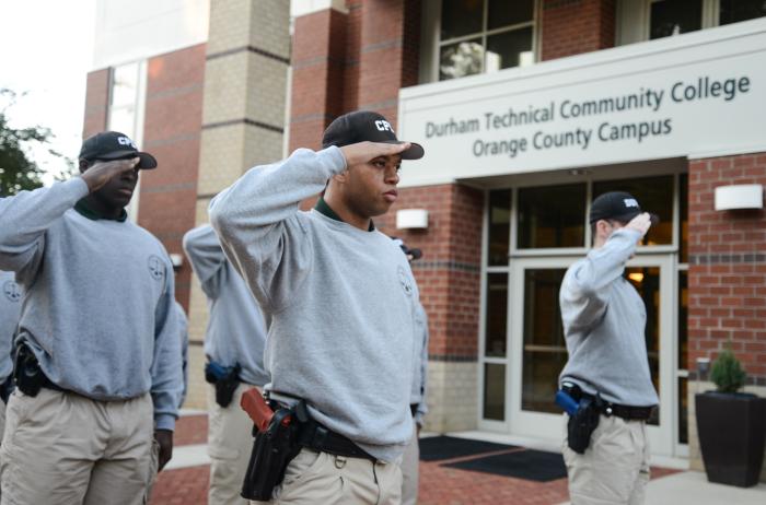 person in basic law enforcement training saluting in front of building