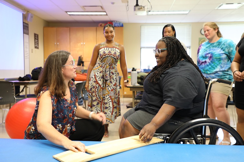 christine in front of student in wheelchair doing demonstration