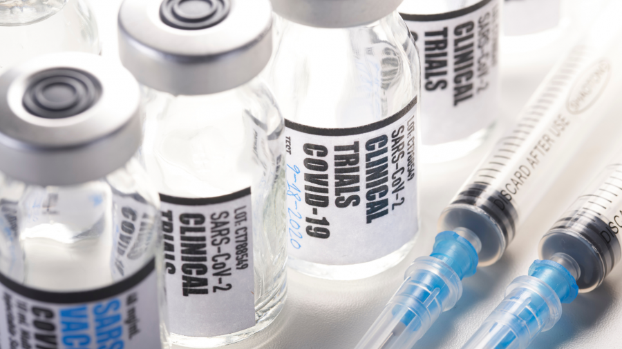 glass bottles that says clinical trials on it and shots laying next to them
