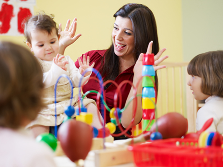 educator playing with a toy with toddlers at a table