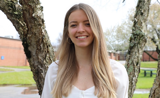 Irina standing in front of tree smiling on campus