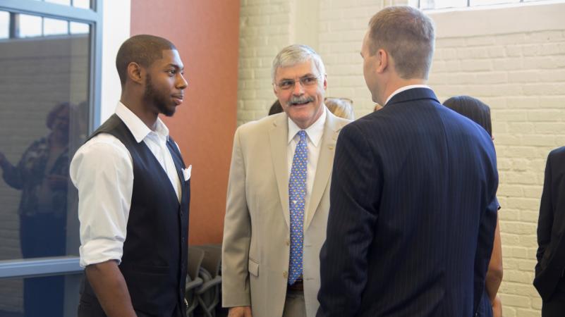 Dr. ingram speaks to two students at an event