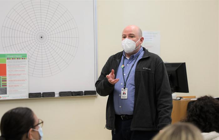 instructor Jim DePalma, wearing a face mask, stands in front of a classroom as he teaches