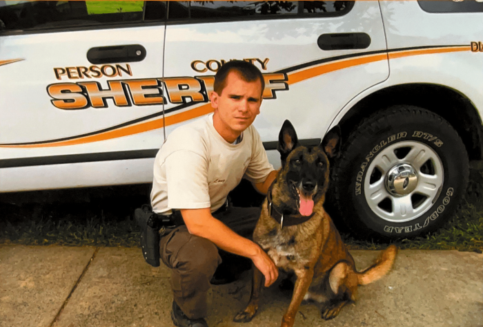 person with dog in front of police car