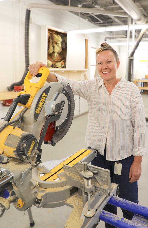 person smiling in front of table saw