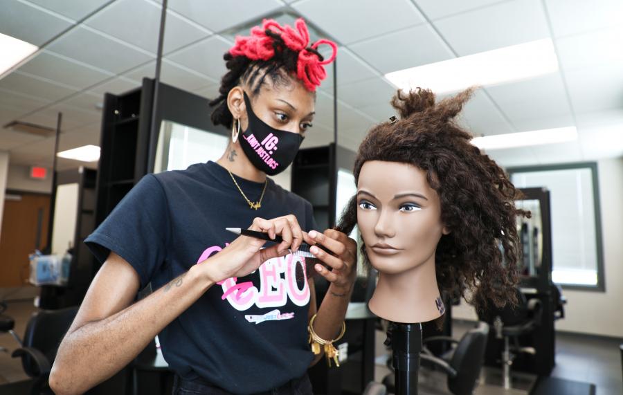 student standing over mannequin styling its hair