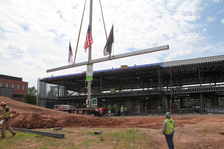 crane holding a construction bar with NC flag, Durham Tech banner, O Brien Atkins Flag, and Bordeaux Construction Flag